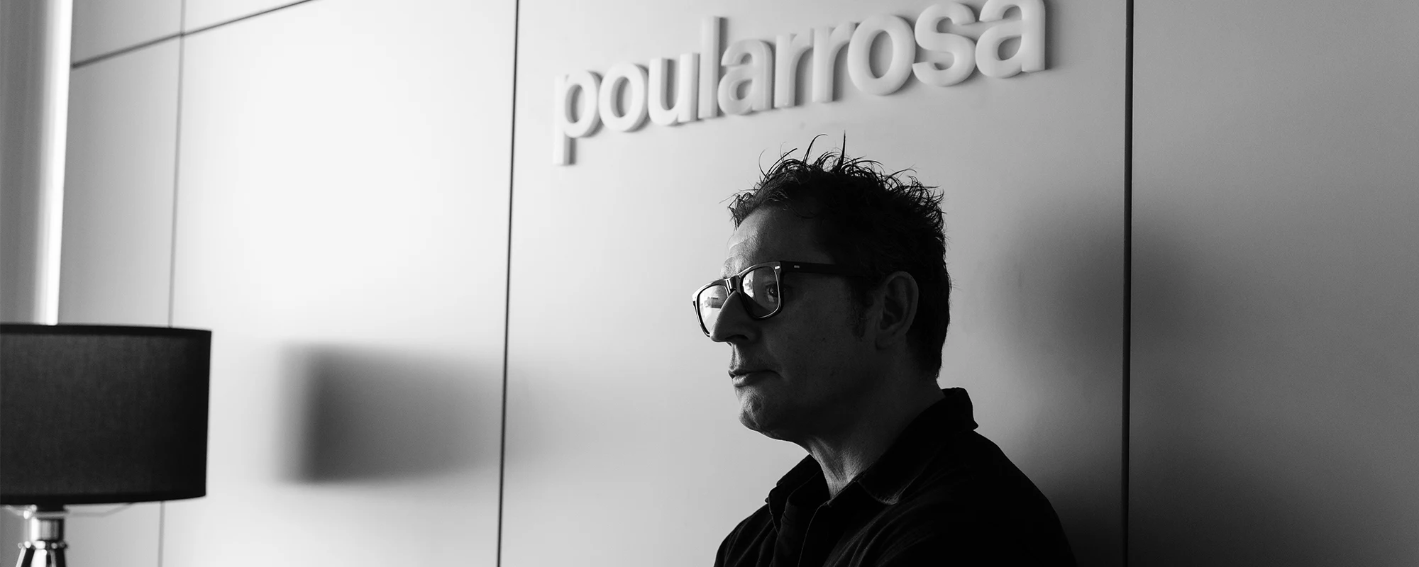 Carlos Pou en el estudio Poularrosa, junto al rótulo corporativo